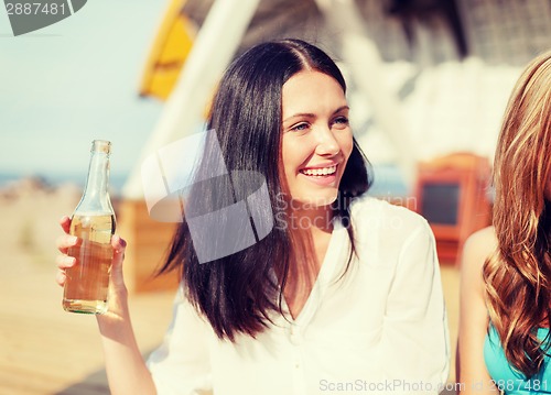 Image of girl with drink and friends on the beach