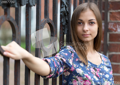 Image of Portrait of a beautiful girl near the old rusty wrought fence