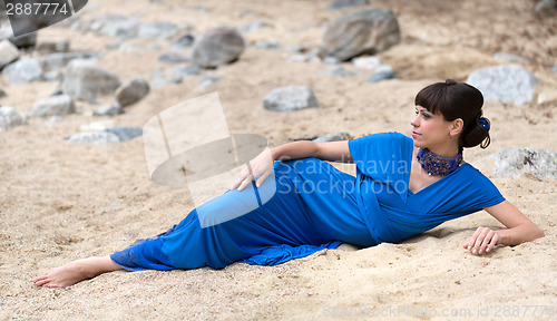 Image of girl in a dress lying on the sand