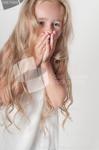 Image of Little girl covers her mouth with her palms