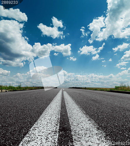 Image of two white lines on black road and dramatic sky with clouds over 