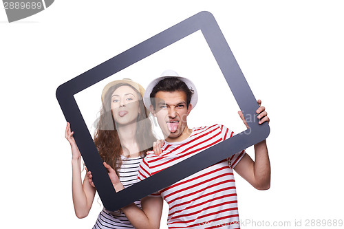 Image of Happy couple showing tongue through tablet frame