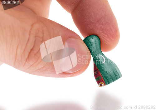 Image of Hand holding wooden pawn, flag painting, selective focus