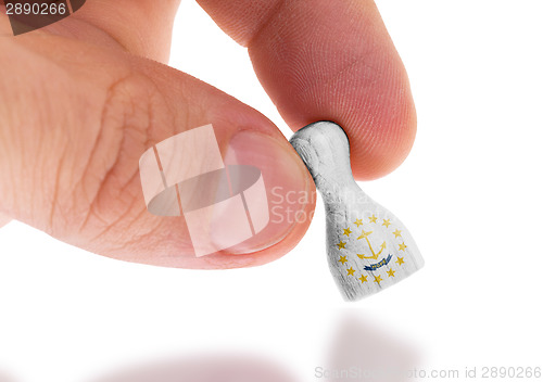 Image of Hand holding wooden pawn, flag painting, selective focus