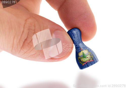 Image of Hand holding wooden pawn, flag painting, selective focus