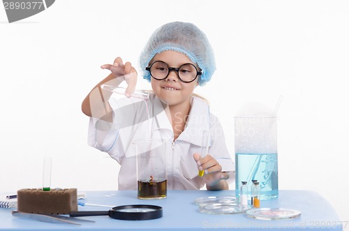 Image of Chemist pours liquid from test tube into a flask