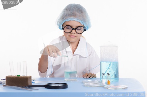 Image of Girl Chemist pours liquid from a test tube into flask