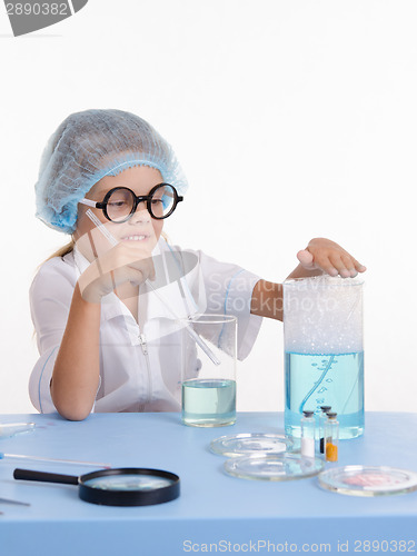 Image of Chemist girl touches foam in flask