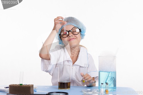 Image of Girl chemist looking at a liquid in test tube