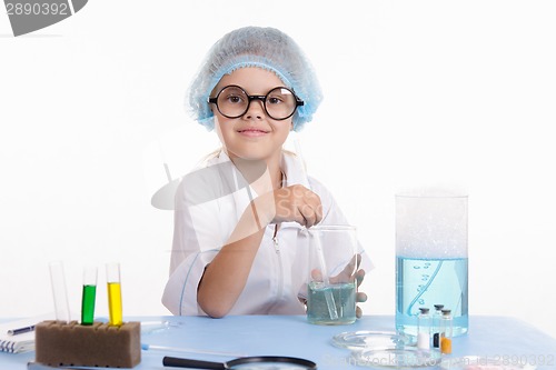 Image of Chemist sitting at table and prevents liquid in flask
