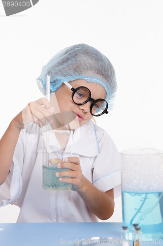 Image of Girl chemist prevents the liquid in flask