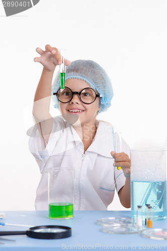 Image of Scientist girl happily looking at test tube with liquid