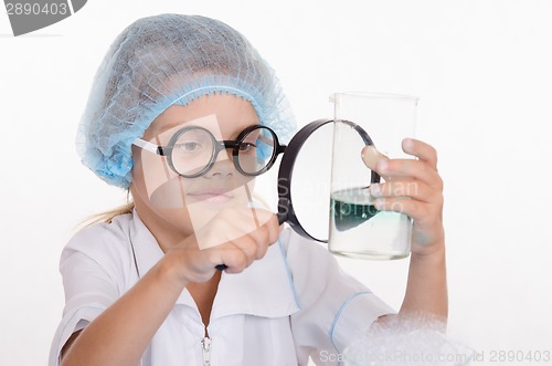 Image of Chemist enthusiasm considering flask under a magnifying glass