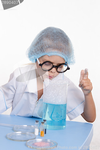 Image of Girl blows foam chemist flask with liquid