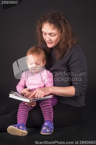 Image of Pretty mother with daughter reading book