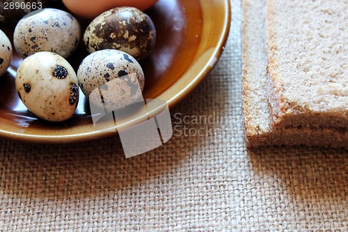 Image of plate with eggs of the quail and piece of bread