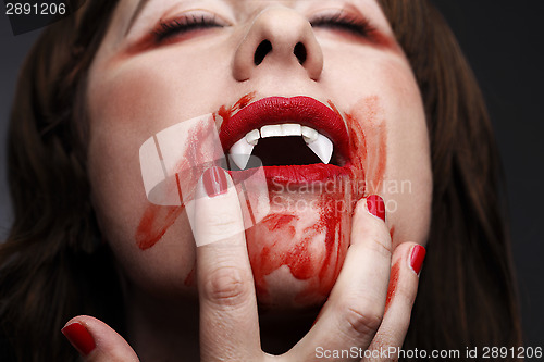 Image of  Female vampire licking blood 