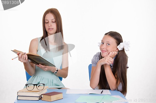Image of The teacher reads student assignments from textbook