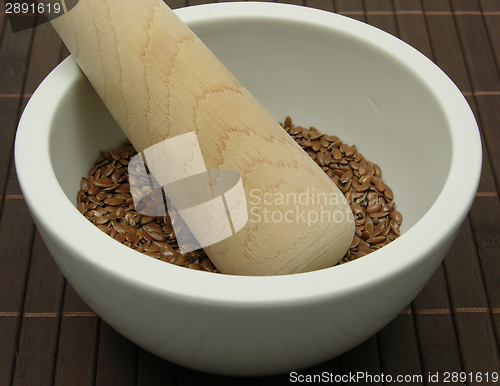 Image of Pestling brown flaxseed in a bowl of chinaware