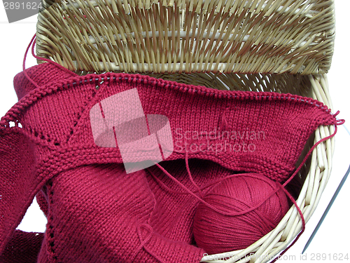 Image of Red knitting with whole pattern in a wooden basket