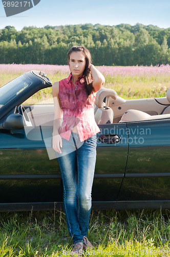 Image of Young woman standing near car