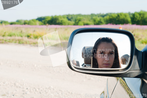 Image of Young woman face in car mirror