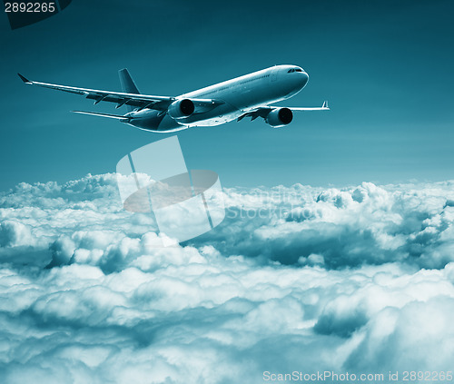 Image of Passenger plane flies over cumulus clouds