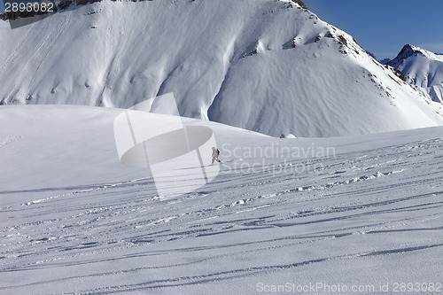 Image of Snowboarder downhill on off piste slope with newly-fallen snow