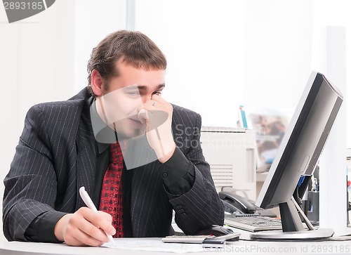 Image of young businessman on workplace in office