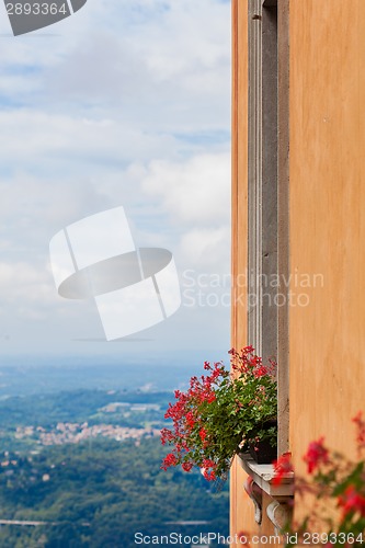 Image of Flowers on the window against view of italian city in mountains