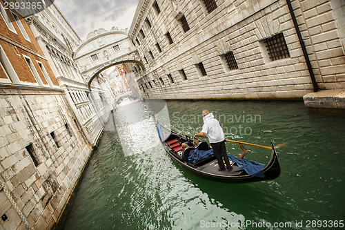 Image of Gondola with gondolier and tourists on the canal in the Venice