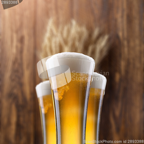 Image of Glass of beer with wheat on wood