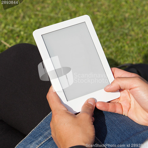 Image of Woman reading ebook on the grass