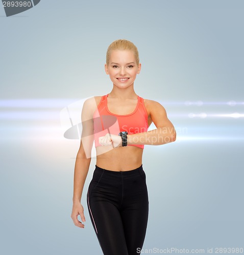 Image of smiling woman with heart rate monitor on hand