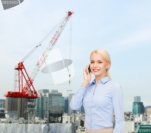 Image of young smiling businesswoman with smartphone