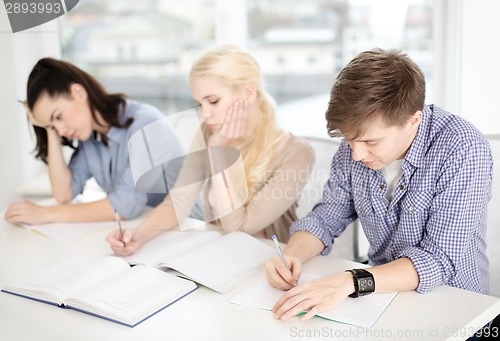 Image of tired students with notebooks at school