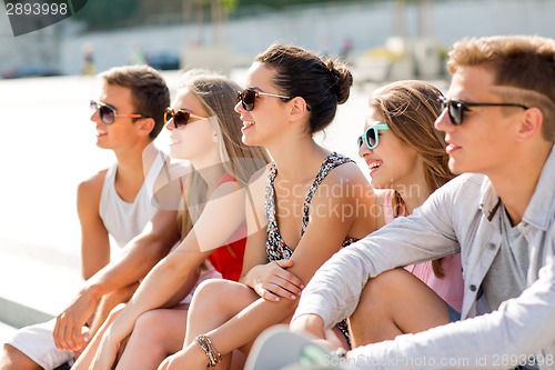 Image of group of smiling friends sitting on city square