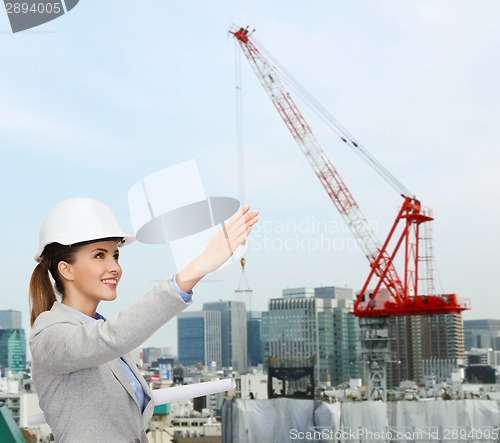 Image of smiling architect in helmet with blueprint