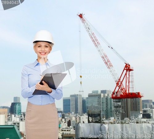 Image of smiling businesswoman in helmet with clipboard