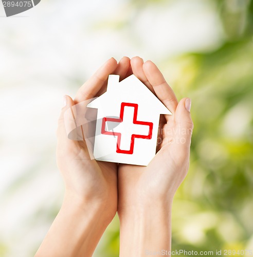 Image of hands holding paper house with red cross