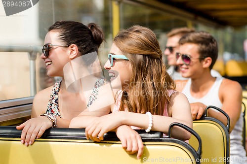 Image of group of smiling friends traveling by tour bus