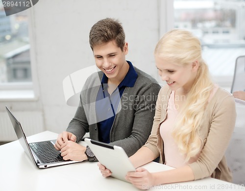 Image of two teens with laptop and tablet pc at school