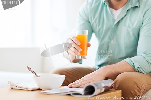 Image of close up of man with magazine drinking juice