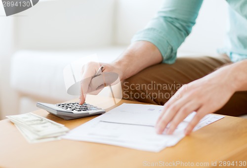 Image of close up of man counting money and making notes