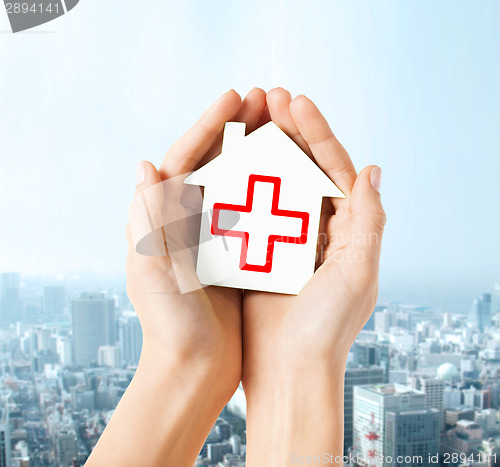 Image of hands holding paper house with red cross