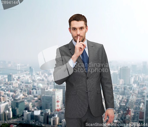 Image of young businessman making hush sign