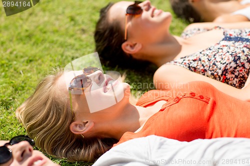 Image of group of smiling friends lying on grass outdoors