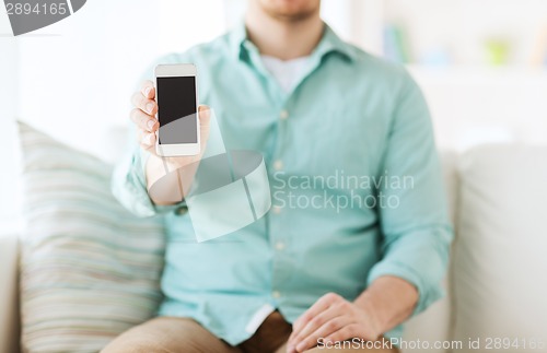 Image of close up of man sitting with smartphone at home