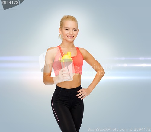 Image of smiling sporty woman with protein shake bottle