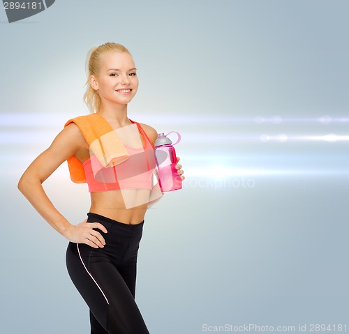 Image of smiling sporty woman with water bottle and towel